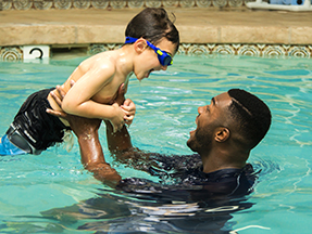 Happy teacher working with student learning to swim