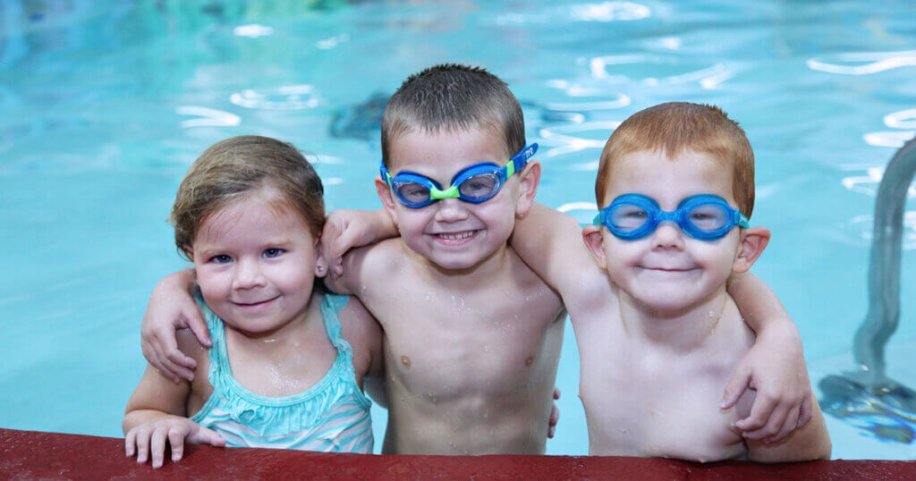 Three kids learning taking swim lessons